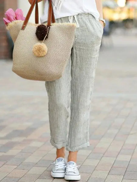 Pantalon lin gris clair femme avec sac paille et baskets blanches, look bohème chic