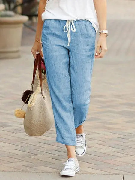 Pantalon en lin bleu clair pour femme, style décontracté avec baskets blanches et sac en paille