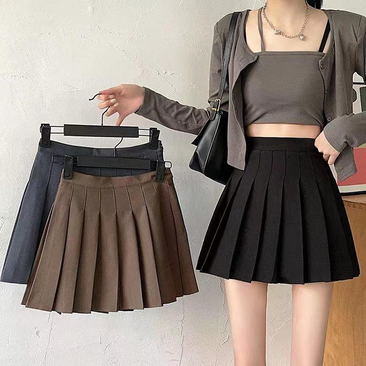 Jupe plissée noire portée avec haut court et cardigan, idéale pour look féminin élégant