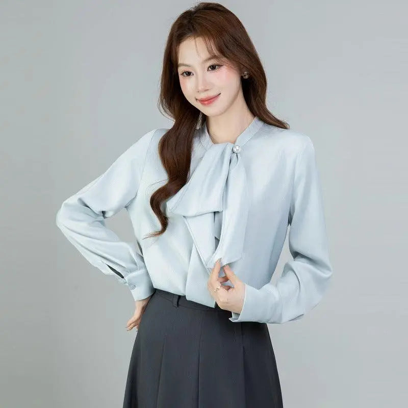 Blouse féminine bleu clair à nœud et manches longues, style élégant pour tenue bureau ou occasion spéciale