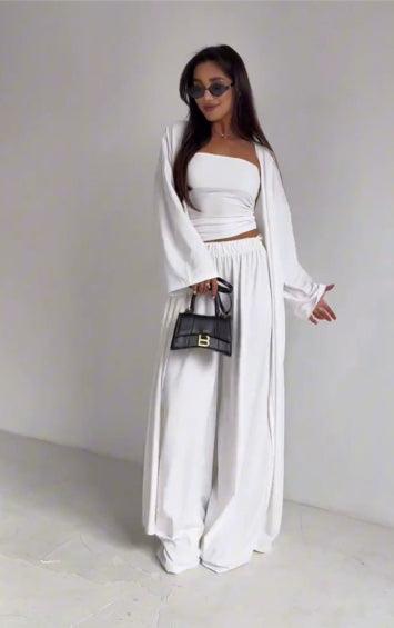 Tenue blanche féminine avec haut crop, pantalon large et veste longue, idéale pour un style bohème chic