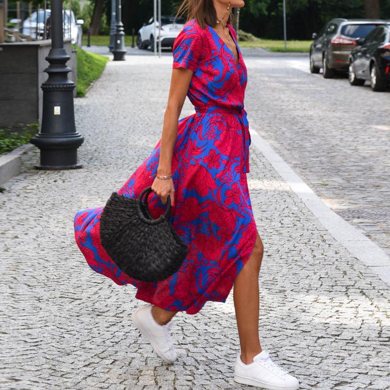 Robe bohème imprimée rouge et bleue, portée avec baskets blanches et sac tressé, idéale pour une tenue féminine chic.