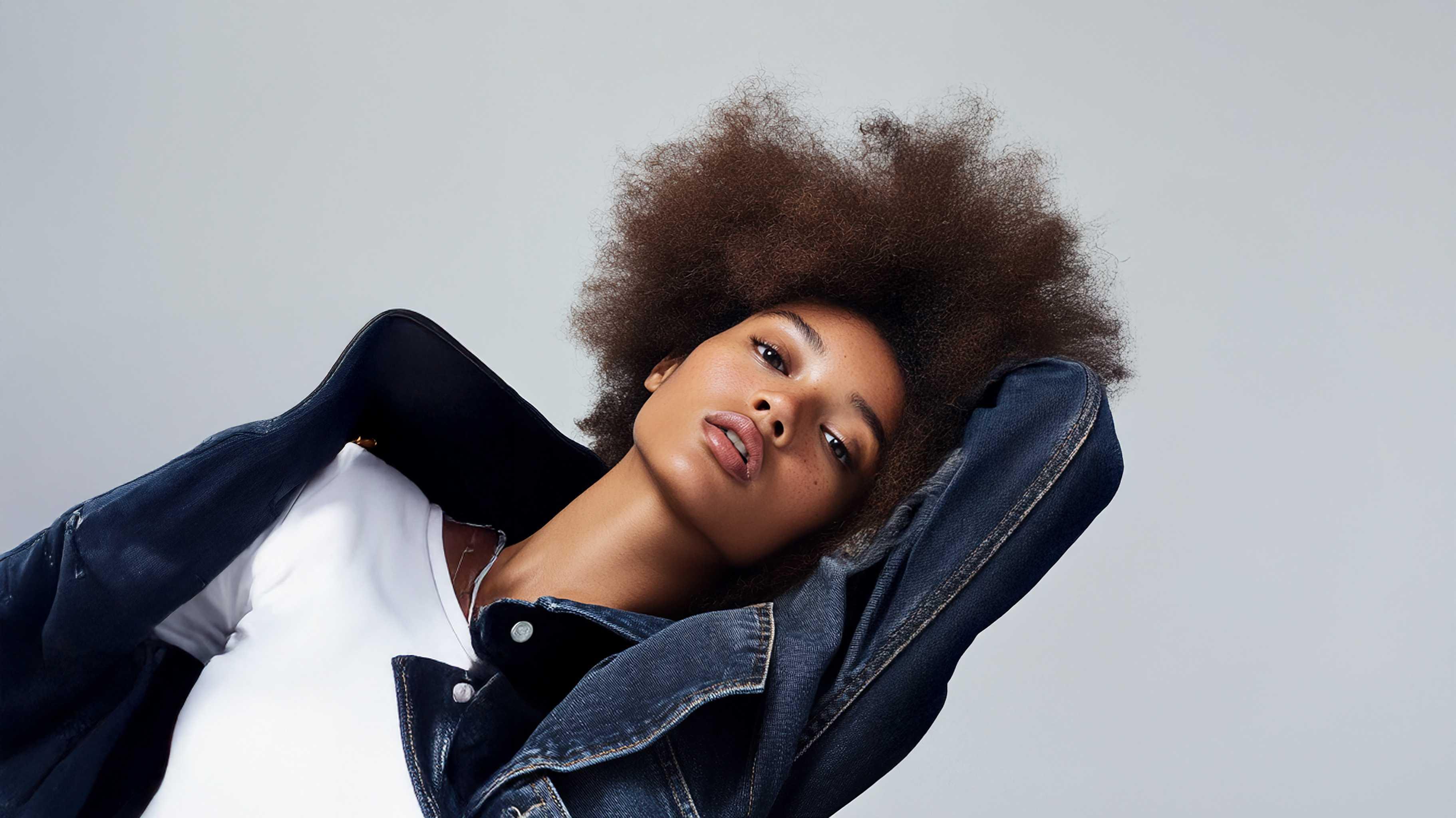 Femme avec afro portant veste en jean et t-shirt blanc, mode féminine décontractée